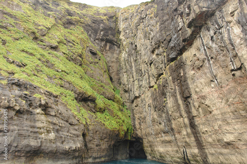 Rocks and caves of the coast near the famous spireTrøllkonufingur  towering rock formation on Vágar Island photo