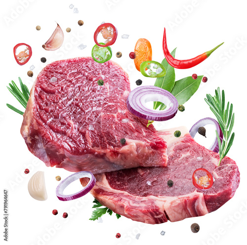 Raw beef steaks, herbs and pieces of vegetables levitating in air on white background. File contains clipping path.