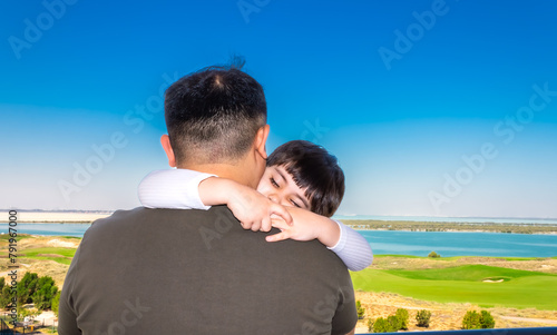a man holds a little girl in his arms on a balcony against the backdrop of a golf course and the sea in the city of Abu Dhabi, a man and a child on vacation