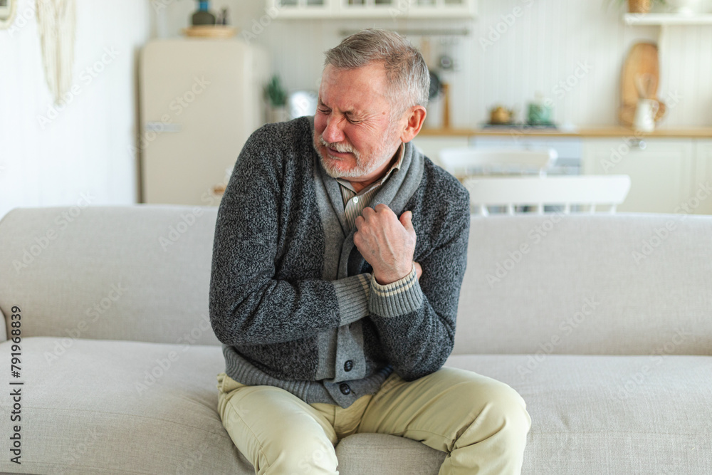 Pain on heart, heart attack. Unhappy middle aged senior man suffering from chest pain heart attack problems with health at home. Mature old senior grandfather touching chest experiencing infarction