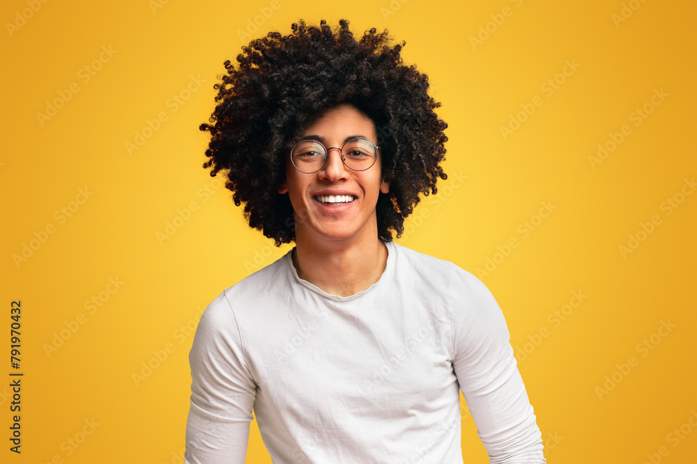 Carefree millennial curly guy posing with hands in jeans pockets Carefree millennial curly guy posing with hands in jeans pockets