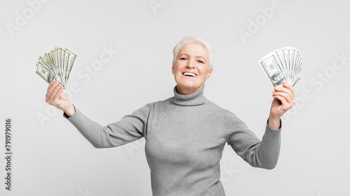 Fotografie Senior joyously showing off her money on grey background