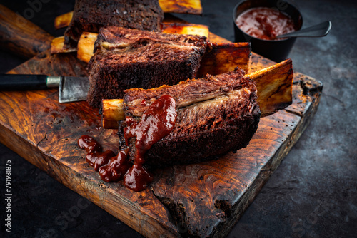 Traditional barbecue burnt chuck beef ribs marinated with spicy rub and served as close-up on an old rustic wooden board with knife  photo