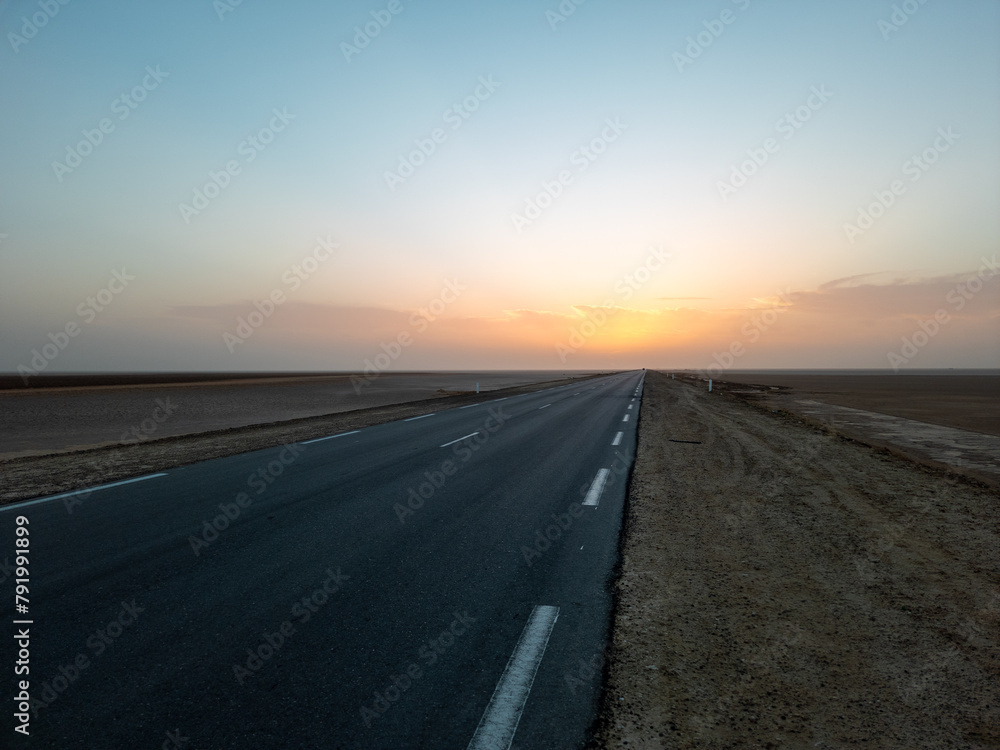 Beautiful colourful sunset over endless empty road in middle of desert. Asphalt highway in Tunisia, North Africa. Beautiful colourful sunset over endless empty road in middle of desert. Asphalt highway in Tunisia, North Africa.