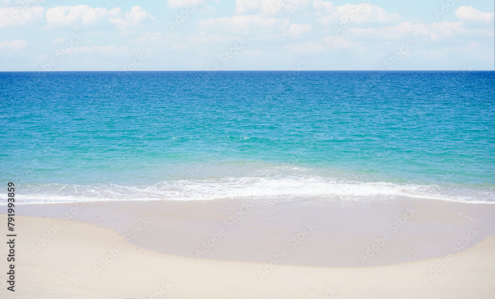 A scenic view of sandy beach and sea foam waves against blue sky with cloud with sunlight background in summer, presenting a breathtaking scenery in Thai Mueang Beach, Phang nga Province, Thailand.