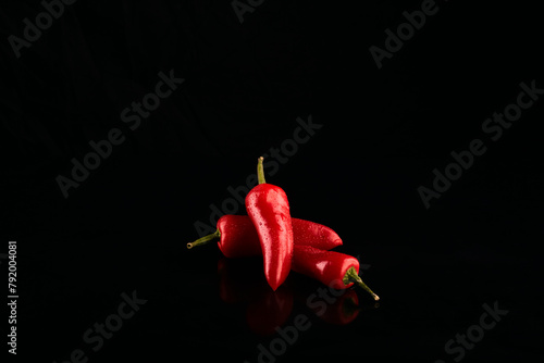 Red chili peppers on a black background. © Mark