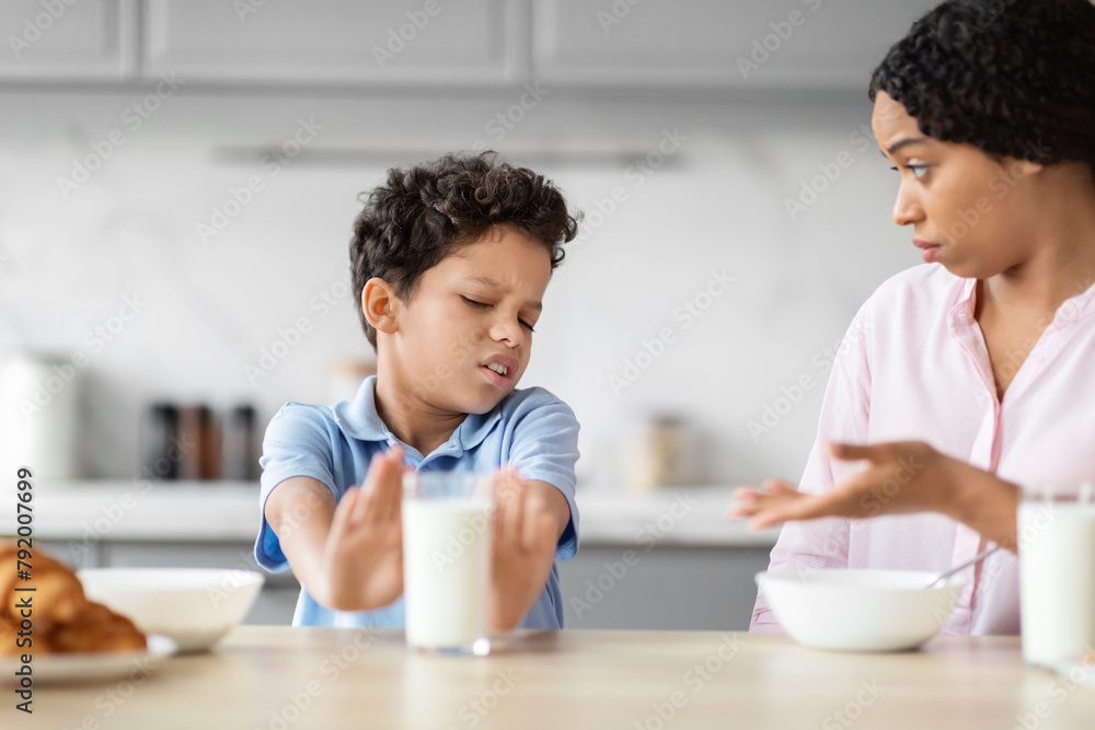 Boy rejecting glass of milk in kitchen scene Boy rejecting glass of milk in kitchen scene