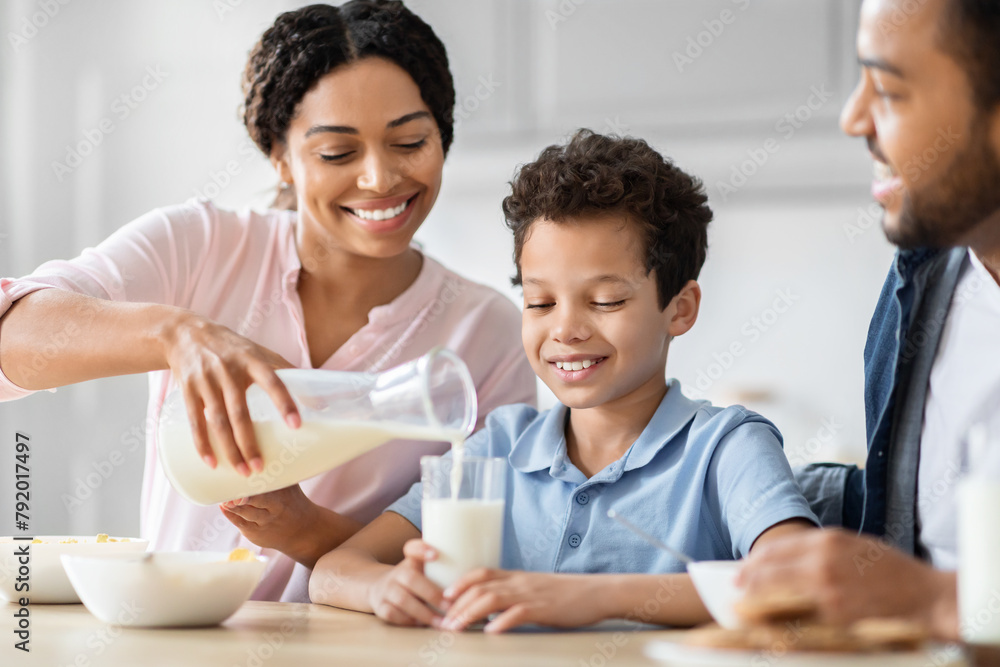 Parent pouring milk at breakfast with family Parent pouring milk at breakfast with family