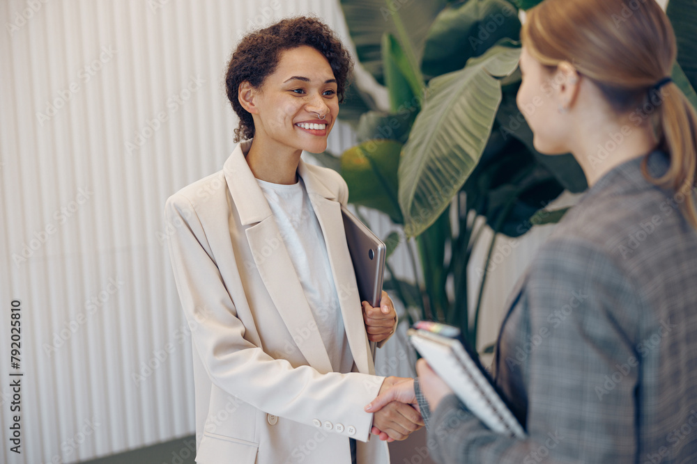 Pretty female entrepreneur is making successful deal with partner shaking hand at work Pretty female entrepreneur is making successful deal with partner shaking hand at work