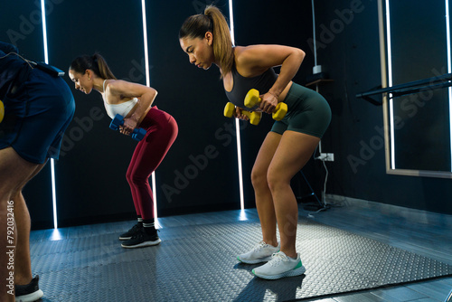 Dynamic group of athletes using dumbbells for their workout in a gym
