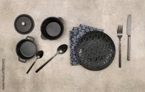 Empty black gray plate, fork; knife, spoon, napkin on marble rustic concrete background. Top view, flat lay.