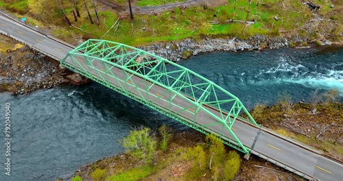 Bridge with a metal construction above narrow river. Some dry wood lies on the waterfront of the river. Top view. photo