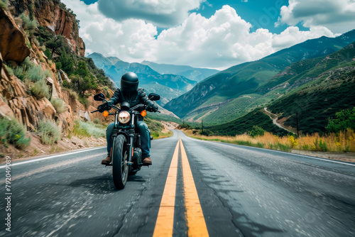 A man is riding a motorcycle down a mountain road. The road is empty and the sky is cloudy. Scene is adventurous and exciting