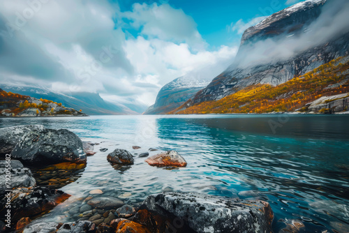 A beautiful lake surrounded by mountains and rocks. The water is calm and clear, reflecting the sky above. The scene is serene and peaceful