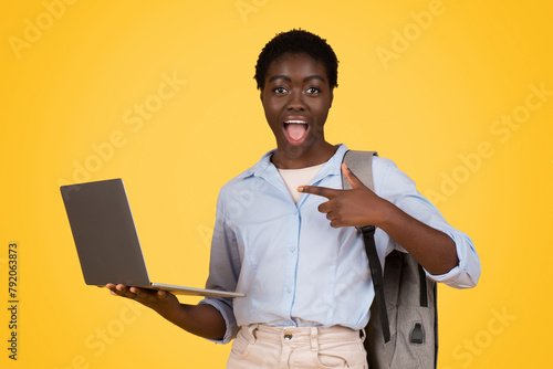 Woman with laptop gives thumbs up on yellow photo