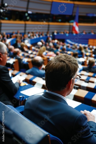 View from behind of an MEP sitting in his seat, surrounded by other politicians, in a plenary session of the European Parliament. Concept of European Union and democracy photo