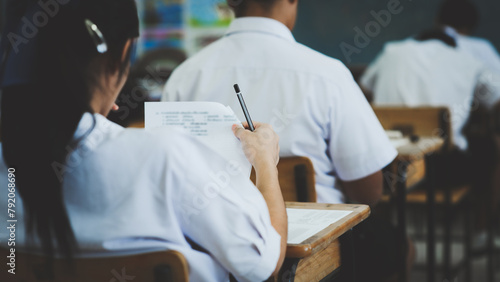 Students take exams with stress in the exam room.A female student thinks by holding a pencil