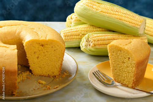  Corn cake on a plate on a yellow marble base, a slice of cake on a plate, ears of green corn on the table.