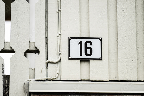 Number 16 on the facade of a baige house.
