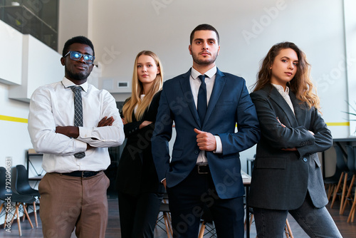 Confident multiethnic business team stands in modern office, poised for leadership. African, caucasian, arabic execs unite, exude corporate success, equity in work environment. photo