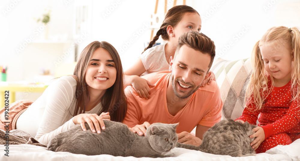 Happy family with cute cats on bed at home