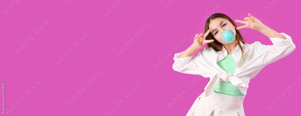 Trendy girl blowing bubble gum while showing victory gestures on purple background Trendy girl blowing bubble gum while showing victory gestures on purple background