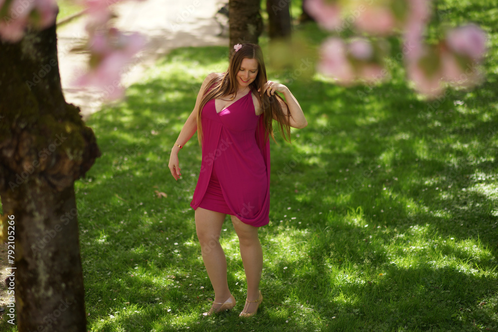 Happy European Woman in Burgundy Dress with Cherry Blossom in Hair Happy European Woman in Burgundy Dress with Cherry Blossom in Hair