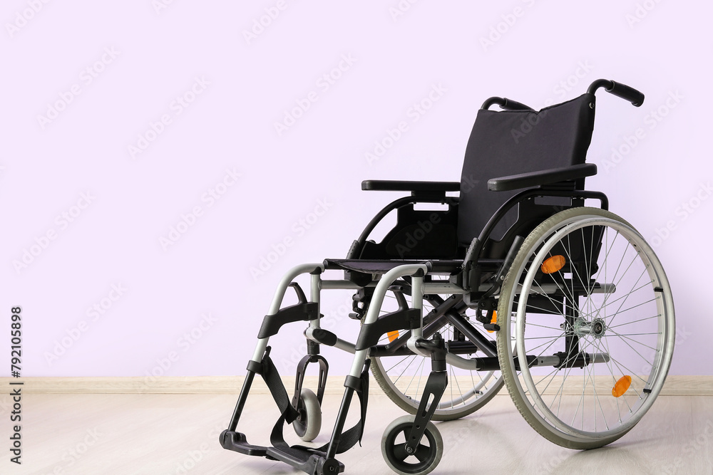 Modern empty wheelchair near lilac wall Modern empty wheelchair near lilac wall