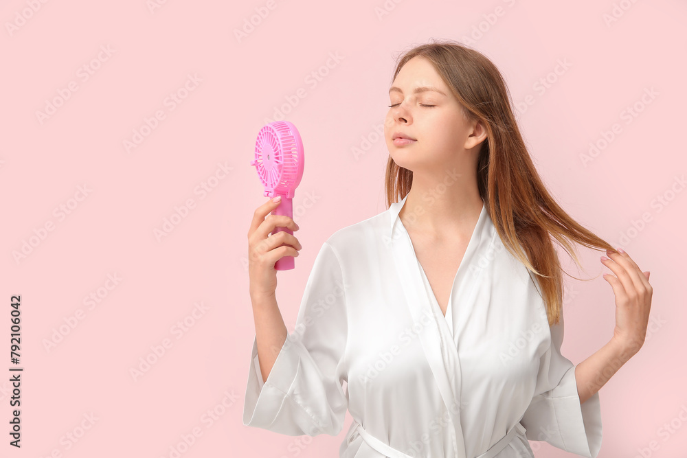 Beautiful young woman with handheld mini fan on pink background Beautiful young woman with handheld mini fan on pink background