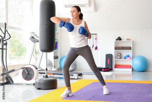 Young woman in boxing gloves training in gym. Concept of self defense