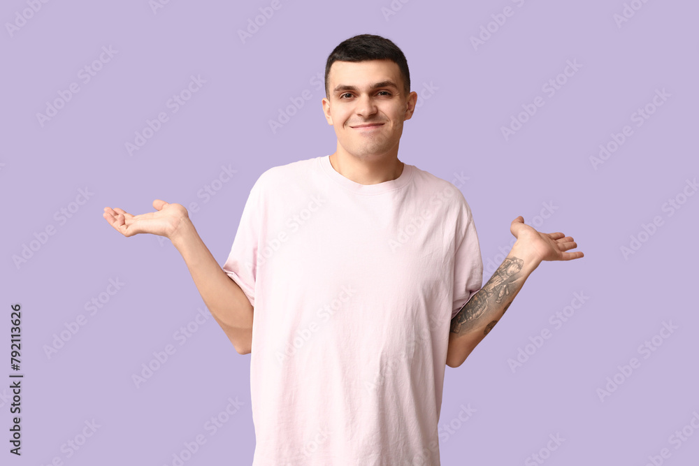 Handsome ashamed young man shrugging on lilac background Handsome ashamed young man shrugging on lilac background