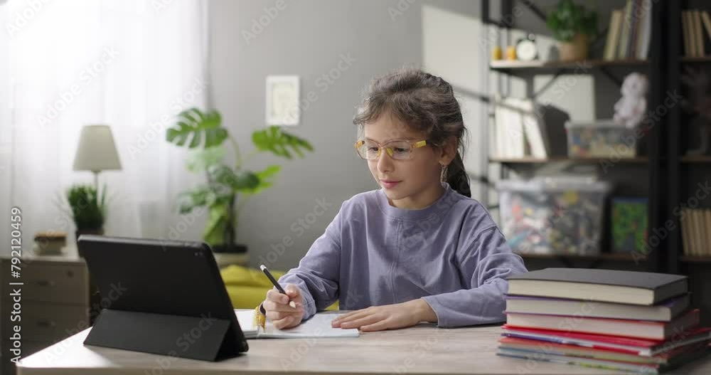 Little girl e-learning online using study app or website on digital tablet. Remote education Little girl e-learning online using study app or website on digital tablet. Remote education