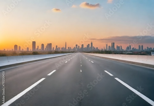 Empty road leading towards a city skyline at sunset, with tall skyscrapers and buildings in the background