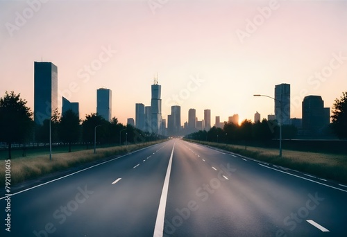 Empty road leading towards a city skyline at sunset  with tall skyscrapers and buildings in the background