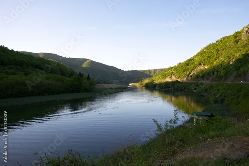 A wide river in the mountains in the rays of the setting sun, an idealistic evening landscape, the tranquil nature of the reserve