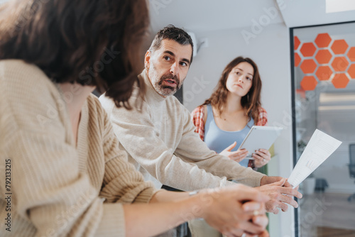 Fotografi A business team engages in a serious conversation with expressions of focus and concern in a brightly lit, contemporary office space, providing a glimpse into corporate dynamics