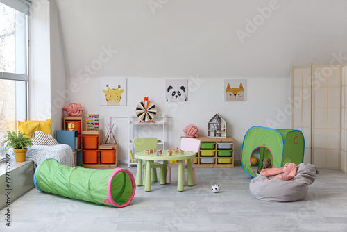 Interior of modern children's room with table and play tunnel