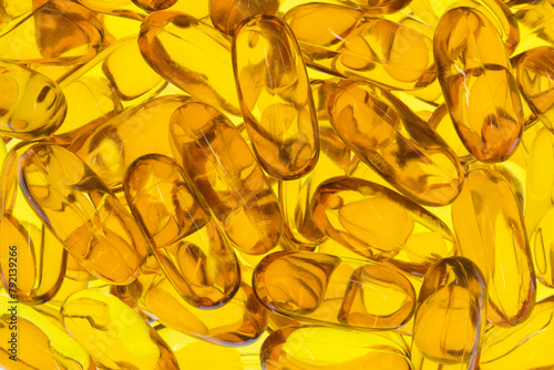 Omega 3 krill fish oil capsules supplements scattered health yellow gold backlit.