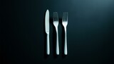 The image features a black background with three white forks and knives on it, giving off an artistic impression rather than depicting a regular mealtime scenario.
