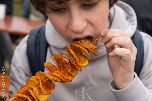 Teenager eating freshly cooked spiral chips.