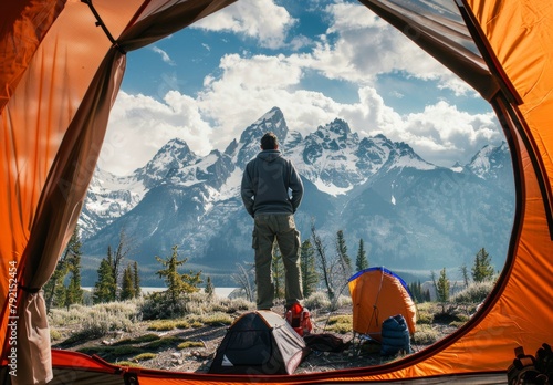 Man Standing in Front of Tent With Mountains in Background