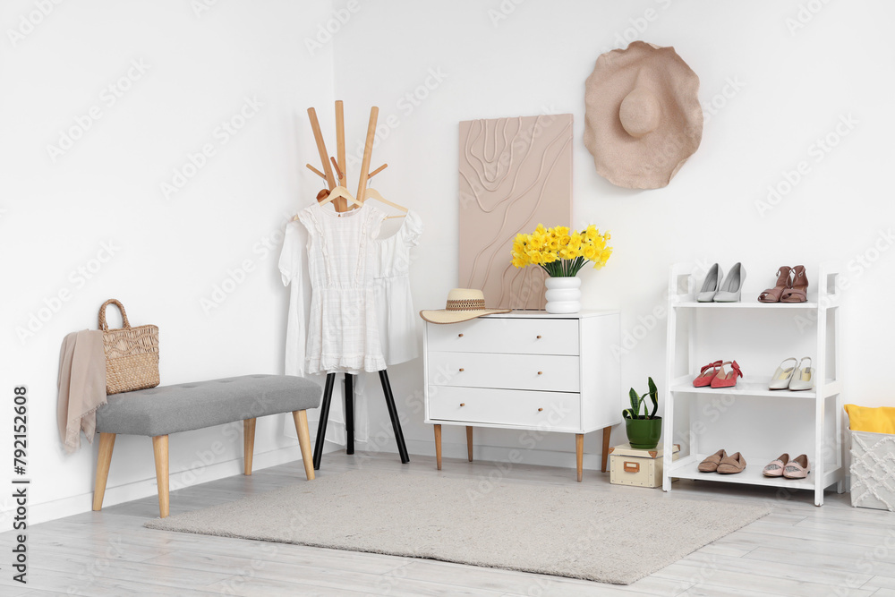 Fototapeta premium Stylish interior of modern hall with bench, chest of drawers and shelving unit