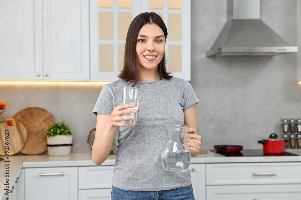 Woman with jug and glass of water in kitchen Woman with jug and glass of water in kitchen