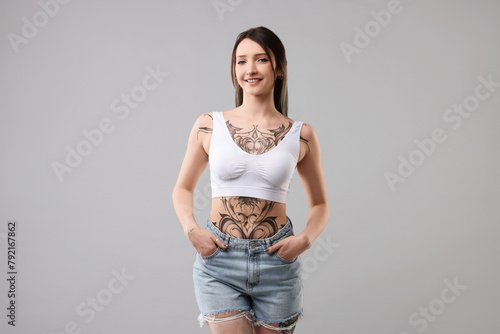 Portrait of smiling tattooed woman on grey background © New Africa