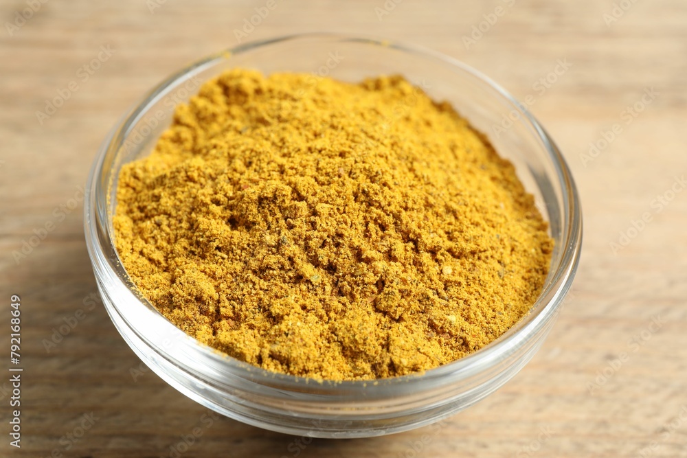 Curry powder in bowl on wooden table, closeup Curry powder in bowl on wooden table, closeup