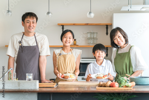 家のキッチンで子供と一緒に料理・クッキング・お手伝いする子供と夫婦・親子・家族 