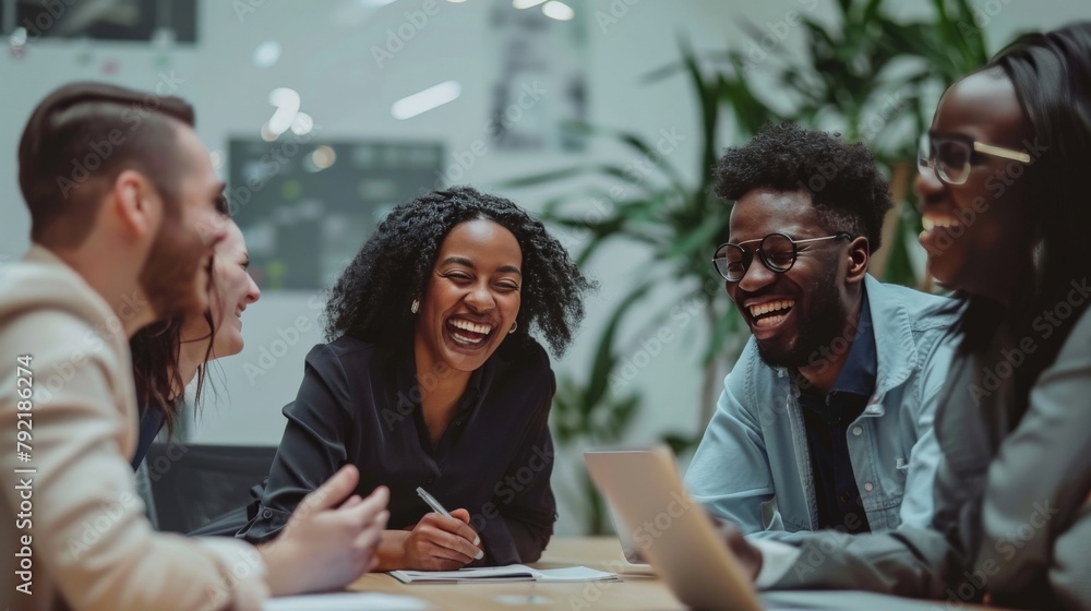Diverse business team laughing together over a shared idea at a conference table in a modern office Diverse business team laughing together over a shared idea at a conference table in a modern office
