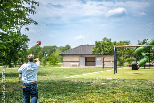 Grandpa playing catch with a football at a park photo