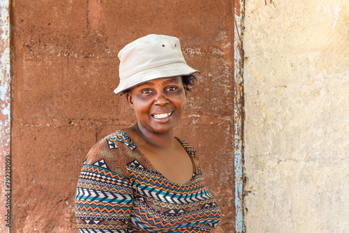 young african chubby woman with a hat in the poor township, informal settlement