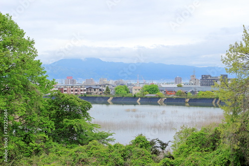 雲がかかった比叡山と麓にわずかに見える琵琶湖、ため池と街の建物